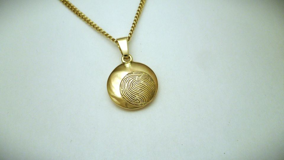 Geelgouden hanger met vingerafdruk en kamertje met as. 18mm rond. Goudsmid Hans Rietman